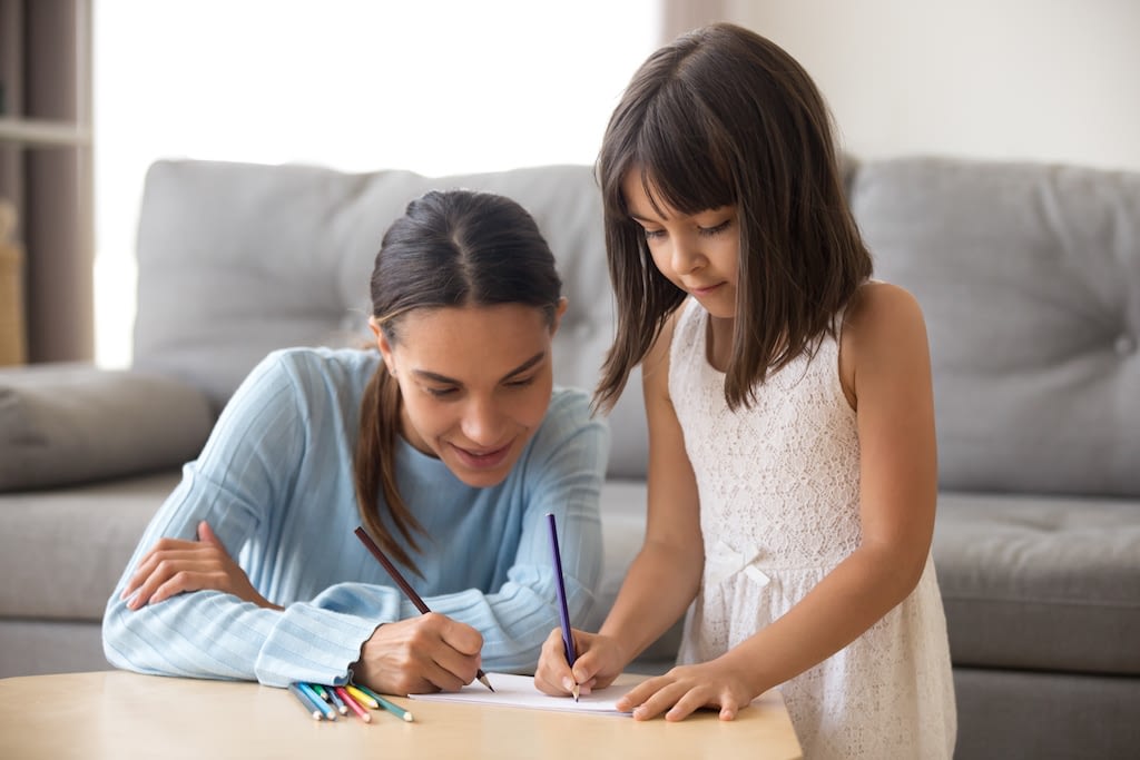 woman and little girl are drawing together at home